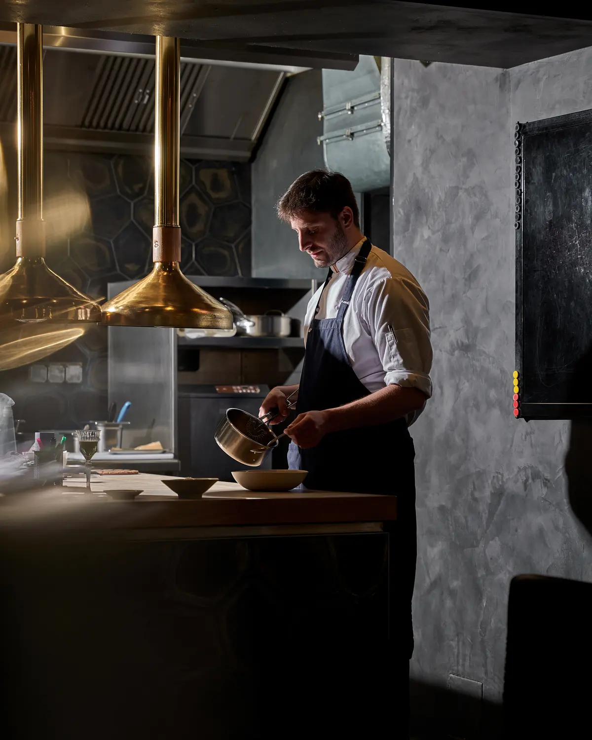Šéfkuchař při přípravě pokrmu v otevřené kuchyni restaurace.